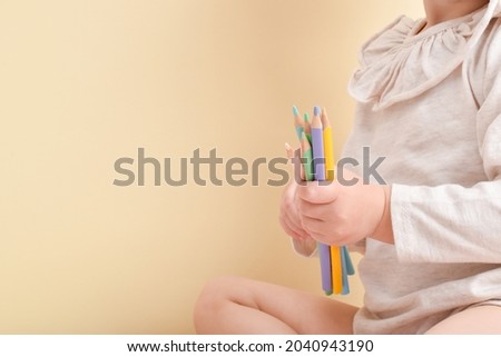A little girl is holding pencils in her hands. Creative classes. Drawing for children. copy space