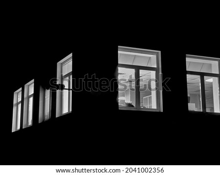 Light from the window of the house late at night. Illuminated night windows of the office. Royalty-Free Stock Photo #2041002356
