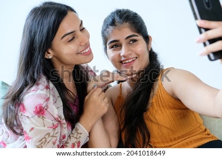 Two Indian best friends happily taking a selfie at home