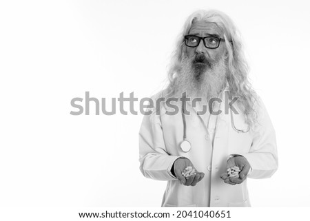Studio shot of senior bearded man doctor isolated against white background in black and white