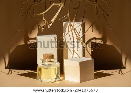 Mock-up of square glass bubble with aromatic oils on background of geometric wooden 3d podiums. Objects reflected in rays of sunlight cast sharp shadow on beige background.Concept of natural cosmetics