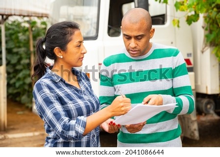Delivery courier invites the farmer to sign documents in the courtyard of country house
