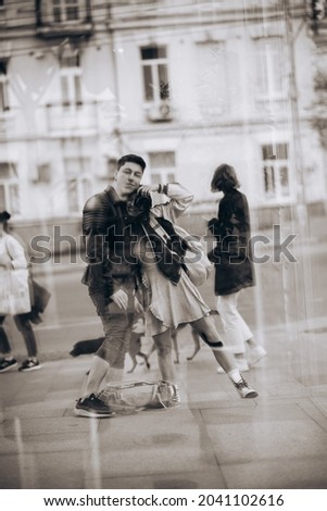 Young couple taking selfie in reflection of glass building