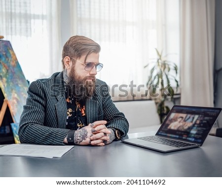Stylish freelancer with beard works on laptop at home in daytime