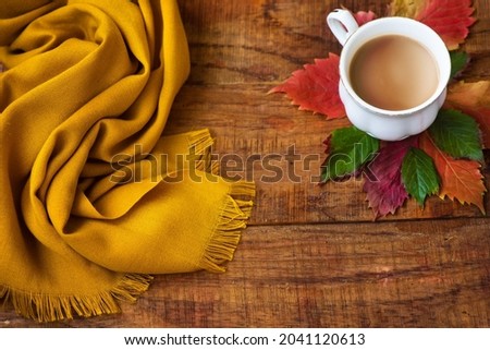 autumn tea cup composition, yellow scarf, leafs on a wooden background. Place for text, copy space Autumn background. Warm, cozy atmosphere of autumn. Flat lay, layout