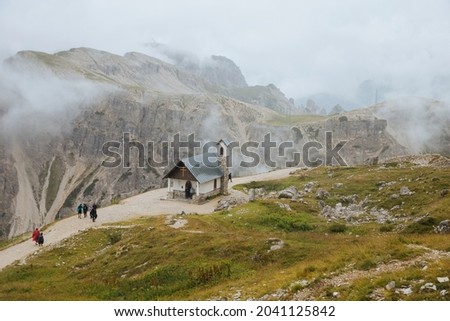 Moody picture of Dolomite peaks. Autumn in Dolomites. Huge peaks in clouds in Italy. Cappella degli Alpini.