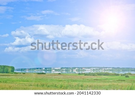Summer landscape - a city on the lake, calm, blue sky with clouds.