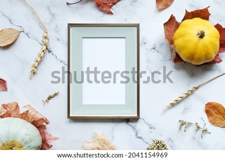 Thanksgiving day, harvesting concept. Blank poster frame and autumn decorations on grey background. Flat lay design. Mockup poster for Thanksgiving day congratulations.