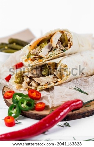 Shawarma with chicken, with sauce, onions, pickles, herbs and hot red pepper on a light background. High quality photo