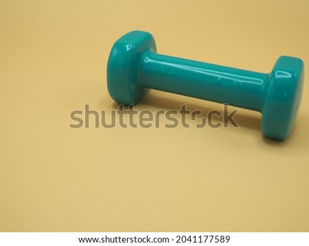 Picture green dumbbell isolated on orange background, Equipment for home workout. Fitness and activity. Sport and healthy lifestyle concept. 