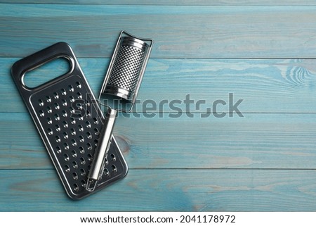 Modern graters on light blue wooden table, flat lay. Space for text