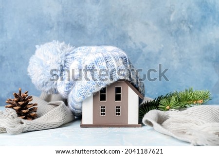 Figure of house and warm clothes on table. Concept of heating season