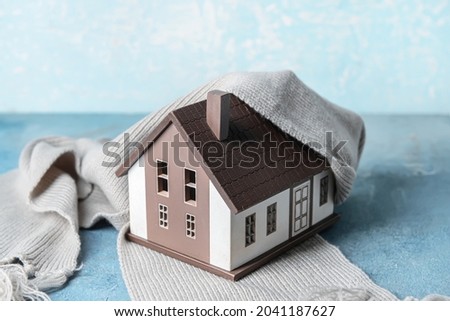 Figure of house and warm scarf on table. Concept of heating season