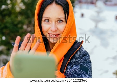 Adult woman making selfie portrait before jogging.Female runner relax after exercising, taking photographs.Active middle age brunette woman posing for selfie image during workout alone in winter time.