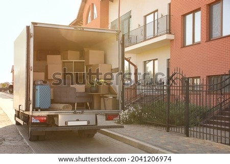 Van full of moving boxes and furniture near house Royalty-Free Stock Photo #2041206974