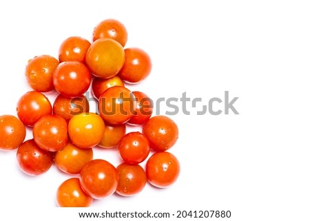 Overhead shot of tomatoes little ones natural reds on a white background. The photograph has copy space and is taken in horizontal format.