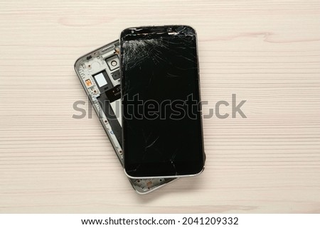 Damaged smartphone on wooden table, top view. Device repairing