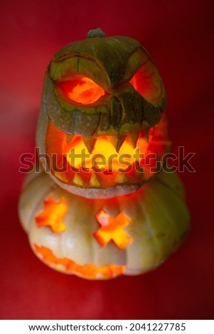 carved pumpkins for the Halloween holiday glows on a red background.
