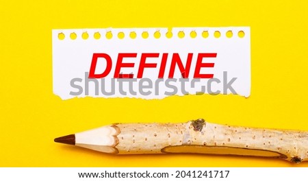 On a bright yellow background, a large wooden pencil and a sheet of torn paper with the text DEFINE