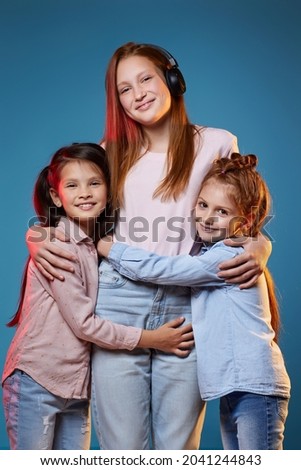 three kids girls standing together on blue background