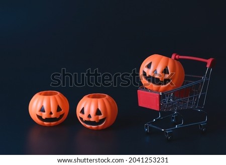 Front view of  Halloween pumpkins on shopping cart  or trolley and on the floor on  black background with copy space. Halloween holiday concept.
