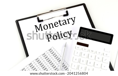MONETARY POLICY text on folder with chart and calculator on the white background
