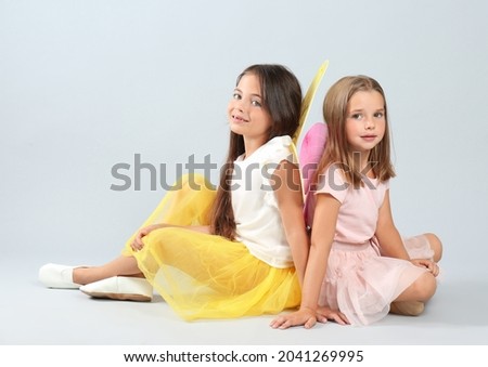 Cute little girls in fairy costumes with wings on light background