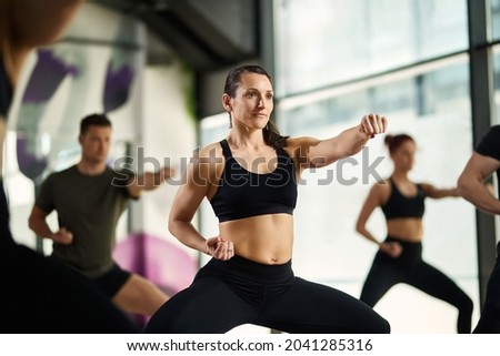 Athletic woman in fighting stance exercising hand punches during martial arts training at health club. Royalty-Free Stock Photo #2041285316
