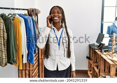 Young african american shopkeeper woman smiling happy talking on the smartphone working at clothing store.