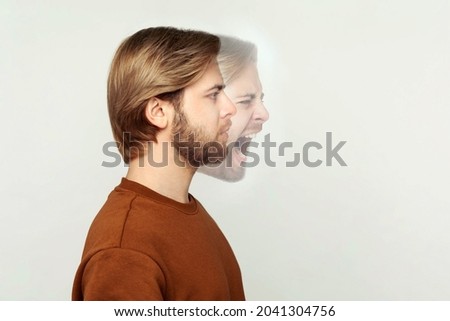 Profile side view portrait of two faced bearded man in calm serious and angry screaming expression. different emotion inside and outside mood of people. indoor studio shot, isolated on grey background Royalty-Free Stock Photo #2041304756