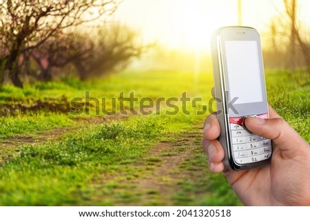 The farmer holds a smartphone and touches the screen on landscape