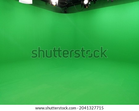 A greenscreen studio with movie lamps on the ceiling.
