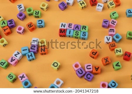 Risk concept.  NEAR MISS letterings on colorful dices on the yellow background. Noise is visible due to the texture of the subject.