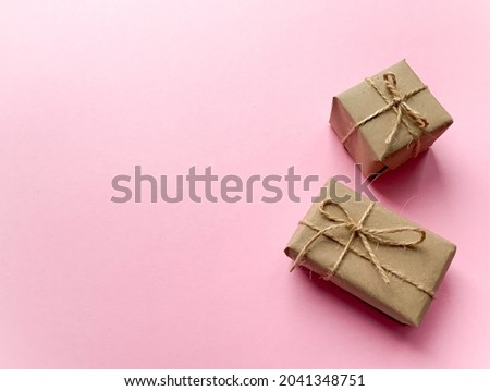 A gift box wrapped in kraft paper on a pink background. View from above, flat lay, top view design. Minimalism. Concept sales, shopping, christmas holidays and birthday.