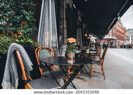 London outdoor coffee and restaurant terrace with tables, chairs and outdoor heater  Royalty-Free Stock Photo #2041351040