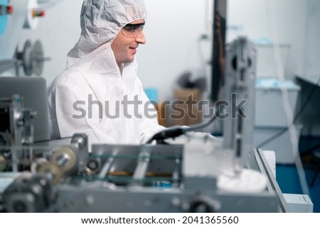 Scientists wearing protective clothing Inspect mask making machines in a laboratory at an industrial plant. Anti-virus production warehouse. concept of safety and prevention coronavirus covid-19.