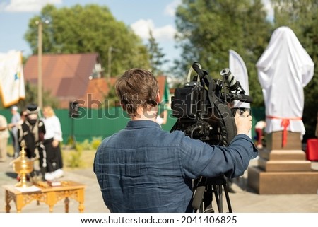 The video operator is shooting. The operator stands near the video camera. The work of the television channel. The man shoots on camera.