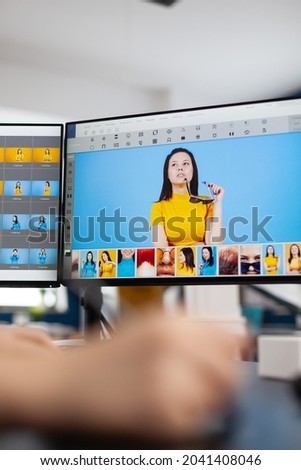 Close up of woman editor retoucher holding stylus pencil moving on graphic tablet editing digital photo using computer with two displays. Photographer retouching assets in production agency