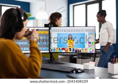 Photographer retoucher with headphones retouching photos using stylus pen drawing on graphic tablet, working at PC with two displays. Creator photo editor working in software app in agency office