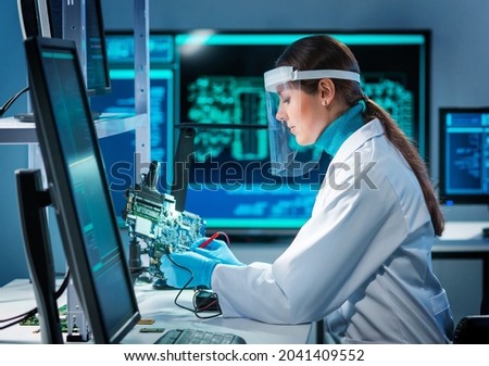 Workplace of young woman in modern microelectronics manufacturing lab. Engineer works in a modern scientific laboratory on computing systems and microprocessors. Royalty-Free Stock Photo #2041409552
