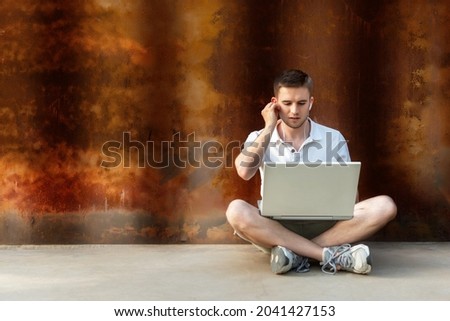 Young man sitting, working with a laptop and talking via video call