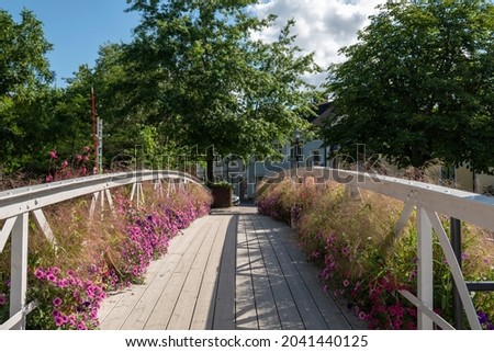 Wooden pedestrian and bicycle bridge over the river of Enkoping beautiful decorated with flowering petunia flowers, picture from Enkoping Sweden.