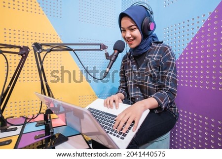 excited muslim woman is recording a podcast in studio with laptop