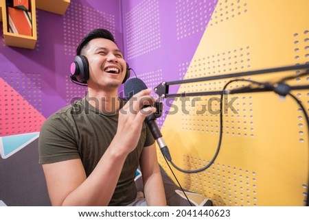 happy asian man is recording a podcast in his studio
