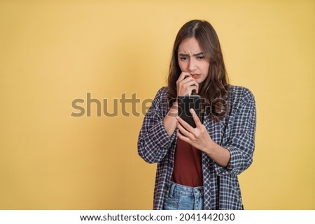 asian woman looking at screen while using a smartphone with worried expression with copyspace Royalty-Free Stock Photo #2041442030