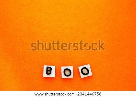 Boo scary concept. Boo word phrase on orange background. Copy space, place for text. Flat lay top view. Minimal Halloween background 