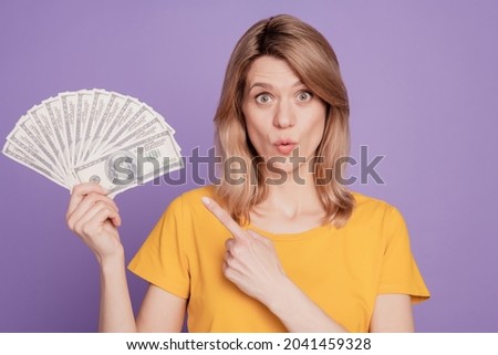 Photo of young pretty woman amazed shocked point finger dollars cash recommend select isolated over violet color background