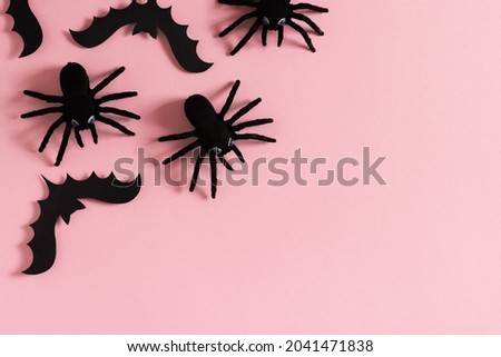 Halloween card with black spiders, bat on pink background, flat lay, copy space, top view