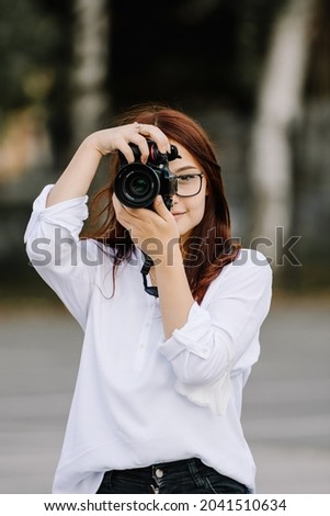 Portrait of a beautiful woman photographer covering her face with the camera.