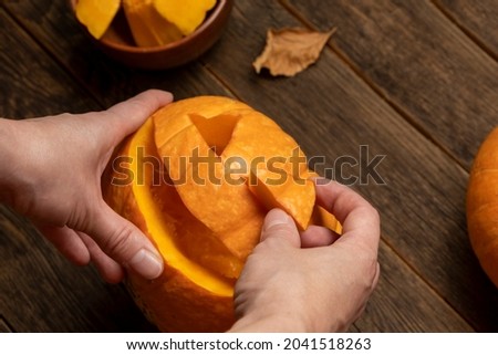 Woman carving pumpkin for Halloween on wooden table